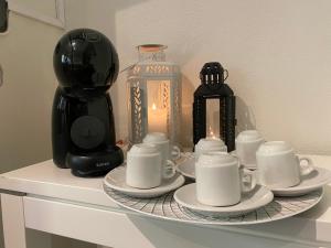 a tray with cups and saucers on a table with a coffee maker at A Berlenga 2 in Nazaré