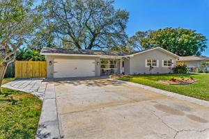 a white house with a driveway in a yard at A Wave From It All in Largo