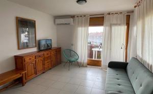 a living room with a couch and a tv and a window at Apartamentos Laura Mar in Palamós