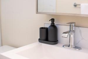 a black soap dispenser sitting on a bathroom sink at Cozy 2 beds Spacious rooms,Close to transit in Vancouver