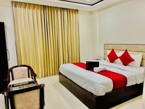 a bedroom with a bed with red pillows and a chair at "Hotel The Lycoris" Near Bus Stand ZIRAKPUR on AMBALA HIGHWAY in Zirakpur