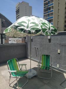 duas cadeiras e um guarda-sol no topo de um telhado em Suítes/Studios Privados Copacabana no Rio de Janeiro
