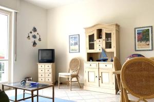 - un salon avec une télévision, une table et des chaises dans l'établissement Appartamento Corallo - WiFi, à Sanremo