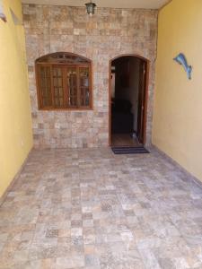 Habitación con pared de piedra y suelo de baldosa. en Meu Aconchego en Cabo Frío