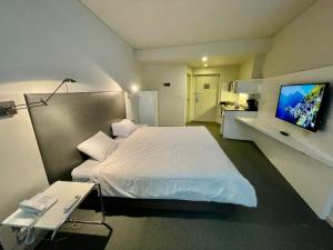 1 dormitorio con 1 cama blanca y TV en Modern Loft in Buenos Aires down town en Buenos Aires