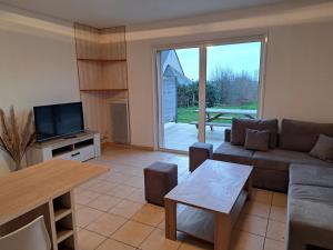 uma sala de estar com um sofá e uma televisão em Cottage Le Cabanon em Huisnes-sur-Mer