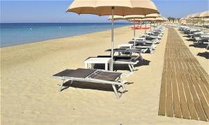 una fila de tumbonas y sombrillas en una playa en 059 e 060 Spiaggia di SalentoinVacanza.Com, en Torre Pali