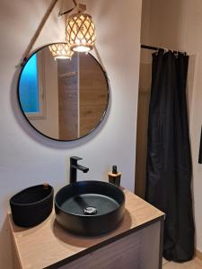 uma casa de banho com um lavatório preto e um espelho em Cottage Le Cabanon em Huisnes-sur-Mer