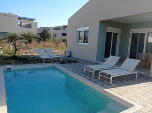 a swimming pool with chairs and a house at Nostalgico cottage in Chania