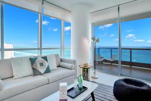 a living room with a white couch and large windows at Dharma Home Suites Miami Beach at Monte Carlo in Miami Beach