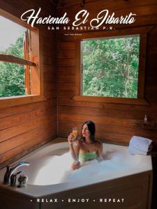 Eine Frau, die in einer Badewanne mit einem Glas Wein sitzt. in der Unterkunft Hacienda el Jibarito in San Sebastian