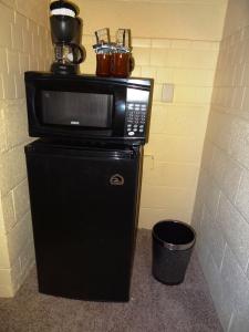 a microwave sitting on top of a refrigerator at JI1, King Guest Room at the Joplin Inn at entrance to the resort Hotel Room in Mount Ida