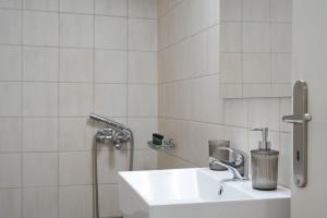 La salle de bains blanche est pourvue d'un lavabo et d'une douche. dans l'établissement Cozy Studio at Ampelokipi Area, à Athènes