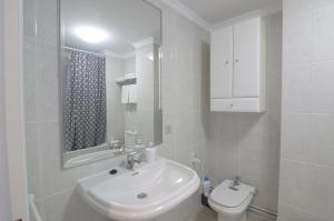 uma casa de banho branca com um lavatório e um WC em Apartamento Playa de Altar em Barreiros
