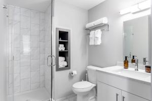a white bathroom with a shower and a toilet at Downtown Vine St Studio at The Guild in Cincinnati