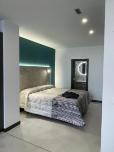 1 dormitorio con 1 cama grande y pared verde en Apartamentos Aljama, en Burgos