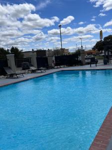 uma grande piscina azul com bancos e um céu nublado em La Quinta by Wyndham Brownwood em Brownwood