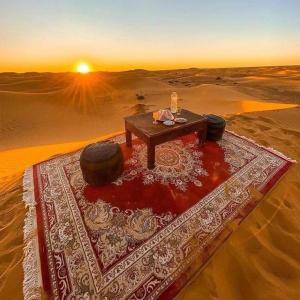 a table in the middle of the desert with two tires at Rainbow Desert Camp in Merzouga