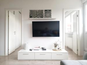 a white living room with a tv on a wall at Nice and Sweet Apartment - self check in in Zagreb