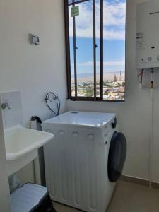 uma casa de banho com uma máquina de lavar roupa e uma janela em Casa de descanso em Caldera