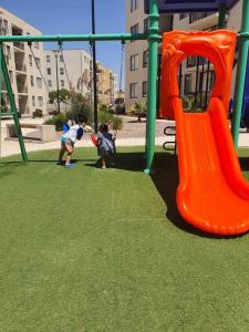 dos niños jugando en un parque infantil con un tobogán en Casa de descanso, en Caldera