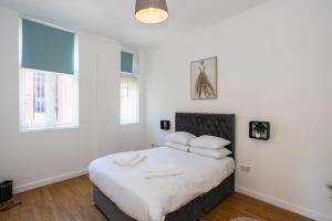 a white bedroom with a bed with white sheets and pillows at Central Liverpool L1 in Liverpool