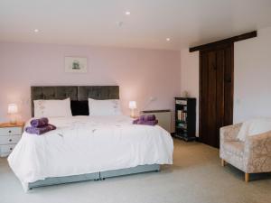 Un dormitorio con una gran cama blanca y una silla. en Stargazer's Field House, en Clifford