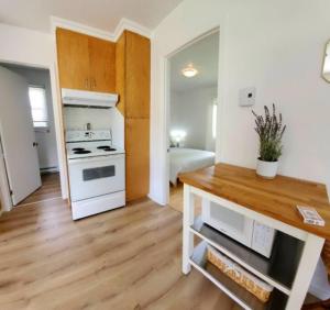 a kitchen with a white stove and a wooden floor at Les Refuges des Monts in Saint-Tite-des-Caps