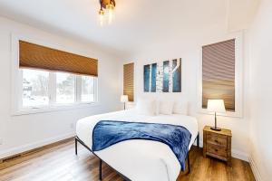 a white bedroom with a bed and two windows at The Cottages at Blue - Cottage 3 in Blue Mountains