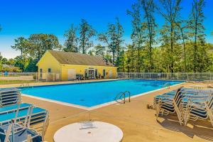 a swimming pool with chairs and a house at Grande at Canal Pointe - 37696 Ulster Dr, Unit #12 in Rehoboth Beach