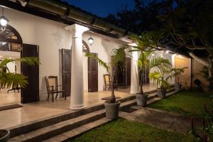 a house with columns and plants in the yard at GALLE HERITAGE VILLA in Galle