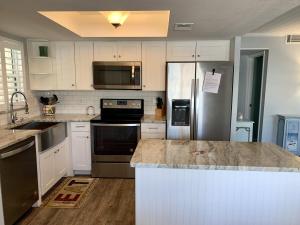 uma cozinha com electrodomésticos de aço inoxidável e armários brancos em Island House Beach Resort V40A villa em Siesta Key