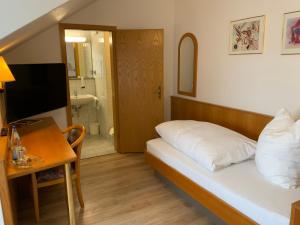 a bedroom with a bed and a desk and a bathroom at Gasthaus Sonne in Hohenstadt
