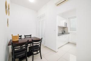 a white kitchen with a wooden table and black chairs at Self check-in apartments by Amber in Bratislava