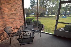 a patio with a table and chairs and a brick wall at 613 River Crossing Condo in North Myrtle Beach