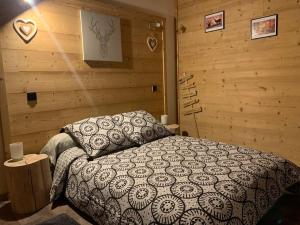 sypialnia z łóżkiem w pokoju z drewnianymi ścianami w obiekcie Appartement de montagne cosy w mieście Angoustrine