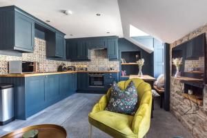 a kitchen with blue cabinets and a yellow couch at Luxury Castle View 3 Bedroom 2 Bathroom Apartment in Edinburgh