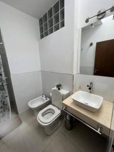 a white bathroom with a toilet and a sink at Alquiler de casa zona Cerro in Córdoba