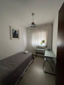 1 dormitorio con cama, escritorio y ventana en Alquiler de casa zona Cerro en Córdoba