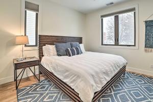 a bedroom with a bed and a nightstand and two windows at Traverse City Condo - Half-Mile to Front Street in Traverse City