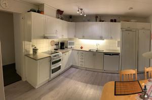 a white kitchen with white cabinets and white appliances at Standard swedish family house in Ronneby