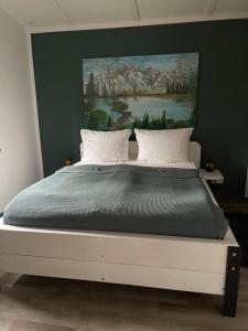 een slaapkamer met een groot bed en een schilderij aan de muur bij Haus Brunhilde in Plodda