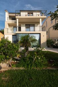 a white building with a balcony on top of it at Apartments Morozin in Krk