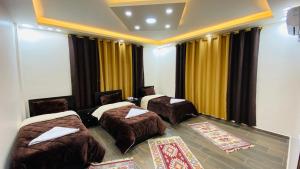 a hotel room with two beds and chairs and curtains at Petra Olive House in Wadi Musa