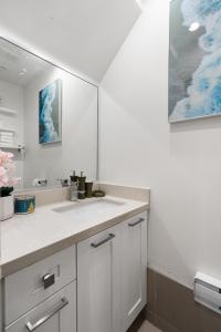 a white bathroom with a sink and a mirror at Parker Guest House in Vancouver