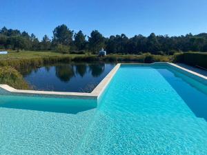 a swimming pool in front of a pond at Casa Vicentina in Odeceixe