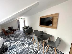 a living room with a table and a tv on a wall at Alpenglühen Smart Hotel in Olching