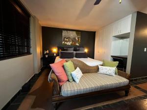 a bedroom with a bed and a couch with pillows at Tranquil Garden Nest in Nelspruit