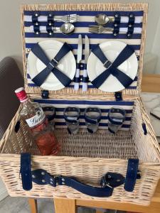 a basket with plates and glasses and a bottle at SWANSEA MARINA VIEW mins to beach, Marina, Swansea Arena, City free parking in Swansea