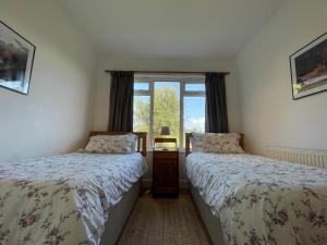 two beds in a room with a window at Jamie's Georgeham in Croyde